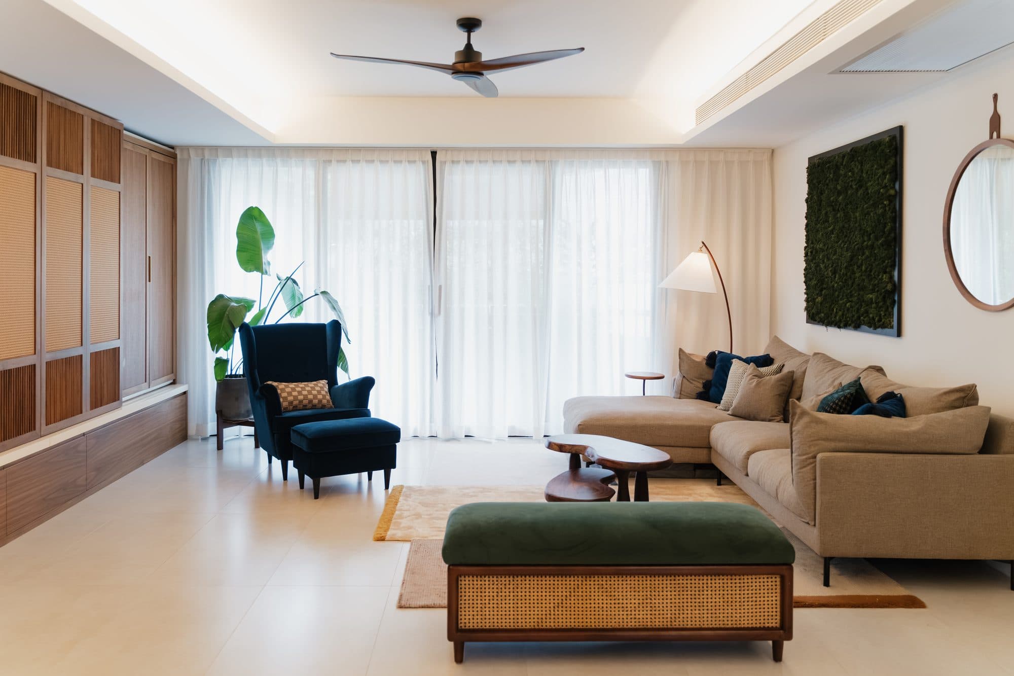 The living room seen along its length, with the full-height walnut joinery wall on the left and the window wall in full daylight